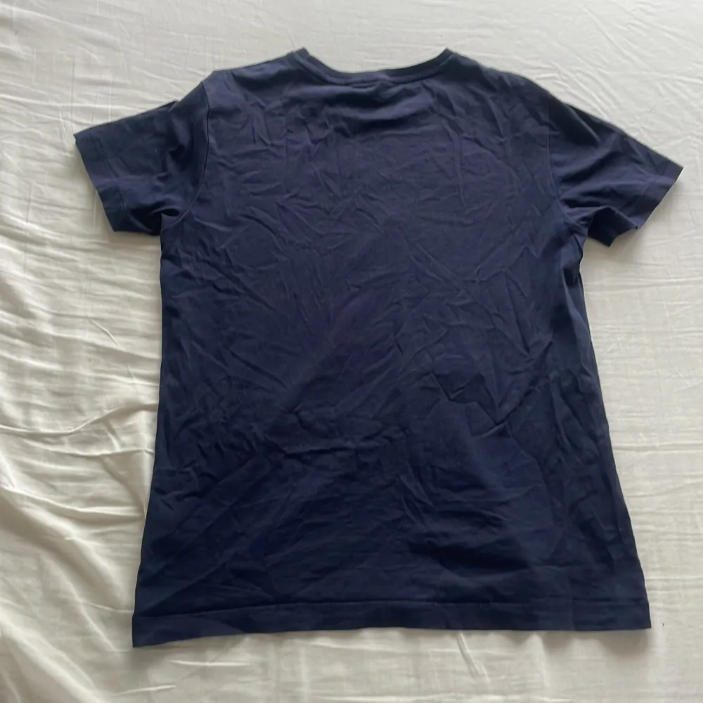 Snygg mörkblå t-shirt från GANT med ett stilrent tryck av märkesnamnet och en sköld med stjärnor och ränder på framsidan. Perfekt för en avslappnad stil.. T-paidat.