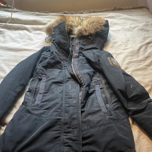 Svart parajumpers med fuskpäls - Säljer en svart parkasjacka från Parajumpers, inga tecken på använd förutom att de är hål i fickorna, och smuts (som går o tvätta bort) är inte säker på om den är äkta. PRIS KAN DISKUTERAS!!!