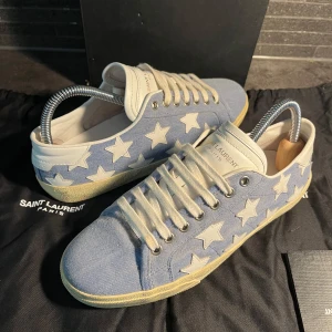 Saint Laurent sneakers med stjärnor - Säljer dessa otroligt snygga och extremt sällsynta limeted edition saint Laurent skorna. Storlek 39 sitter som 39-40. Skick otroligt bra använda en handfull utav gånger 9/10. Box följer med vid köp, nypris 8000kr hör av er vid frågor.