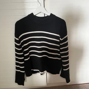 Svartvit randig stickad tröja Gina Tricot - Snygg svart stickad tröja med vita horisontella ränder. Tröjan har en rund halsringning och långa ärmar. Perfekt för dig som gillar en klassisk och stilren look med en twist. Ribbstickade muddar vid hals, ärmslut och nederkant. Tröjan har en slit på båda sidorna som gör tröjan lite speciell. Tröjan är från Gina Tricot i storlek xs och har använts få gånger.