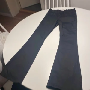 Svarta bootcut jeans från Lindex - Snygga svarta jeans från Lindex med bootcut-modell och klassisk femficksdesign. Byxorna har normal passform och är tillverkade i ett mjukt bomullsmaterial med lite stretch. Perfekta för dig som gillar en tidlös look med lite utsvängda ben. Storlek 152. 