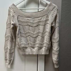 Beige stickad offshoulder tröja M  - Superfin beige stickad tröja med offshoulder-modell och snyggt hålmönster. Tröjan har långa ärmar och bred ribbad kant vid halsen och nederkanten. Perfekt för dig som gillar en chill och trendig look. Storlek M