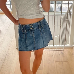 Blå jeanskjol med fickor och knappar - Säljer en snygg blå jeanskjol i kort modell med dubbla knappar framtill, coola fickor bak med lock och knappdetaljer. Kjolen har rå kant nertill och markerade sömmar för en trendig look💙lite stor på mig passar nog s-m