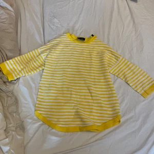 Gul- och vitrandig tröja från Object - Superfin gul- och vitrandig tröja från Object med rund halsringning och trekvartsärm. Tröjan har en avslappnad passform och är gjord i mjuk bomull, perfekt för vår och sommar. Storlek S