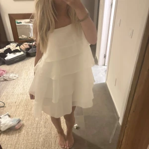 Vit volangklänning med axelband - pris kan diskuteras vid snabb affär ❌Superfin vit kortklänning med flera lager volanger och tunna axelband. Klänningen har en luftig och flowy känsla, perfekt för varma dagar. Den är ärmlös och har en lätt A-linjeformad siluett som ger en söt och somrig vibe.