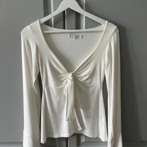 Maddy blouse från design by si - Vit maddy blouse med lång ärm och snygg knytning framtill. Djup v-ringning och mjukt, stretchigt material som sitter skönt. Storlek xs/s och aldrig använd💕