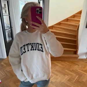 Vit sweatshirt från EDIKTED - Vit sweatshirt från EDICTED med svart tryck framtill. Klassisk rund halsringning och ribbade muddar vid ärmslut och nederkant. Skön och avslappnad passform, perfekt till jeans eller leggings.köpt av filli 