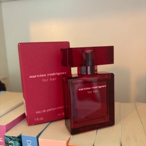 Narciso Rodriguez For Her parfym - En elegant parfym i en djup röd glasflaska med matchande röd kartong. Flaskan har en stilren, fyrkantig form och tydlig logga framtill. Doften är eau de parfum intense och passar dig som gillar lyxiga och feminina parfymer. Endast testad