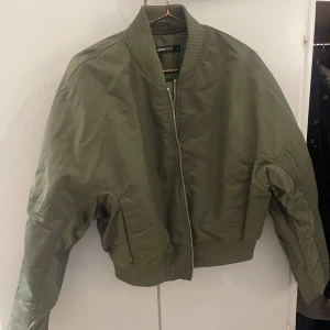 Bomberjackor i grönt och svart - Fyra snygga bomberjackor i olika nyanser av grönt och svart. Klassisk modell med dragkedja, ribbade muddar och fickor. Perfekt för dig som vill ha en stilren och trendig jacka till vardags. Materialet är polyester och jackorna har lång ärm. Vissa aldrig använda!