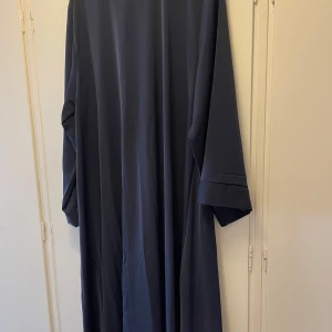 Marinblå abay med vida ärmar - Säljer en marinblå abaya med riktigt snyggt fall och vida ärmar. Klänningen har en enkel och stilren design, perfekt för dig som gillar modest mode. Materialet känns mjukt och följsamt mot huden. Passformen är loose och klänningen är helt enfärgad. Den passar längder 160-170 och storlekar S-L pga hur loose den är 💕 Pris kan diskuteras!