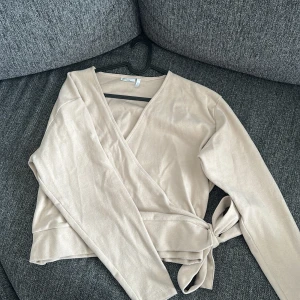 Omlottkofta från Asos - Jättesöt omlottkofta i beige från Asos Design! Jättemjukt material! Storlek m men kan sitta som S också! Aldrig använt!