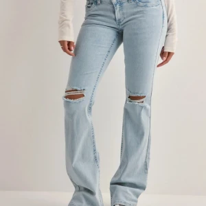 Ljusblå bootcut jeans med hål - Populära blåa jeans från Nelly med hål. Fransarna i hålen är borta och dem är lite slitna längst ner vid fötterna där bak💕💕💕