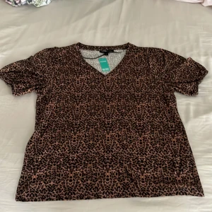 Leopardmönstrad topp från Mywear - Snygg topp från Mywear med leopardmönster i brunt och svart. Modellen har v-ringning och korta ärmar, perfekt för dig som vill sticka ut lite extra. Tillverkad i mjuk bomull som känns skön mot huden.