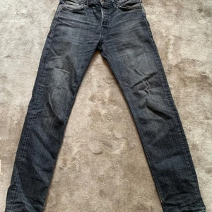 Mörkgrå jeans från Jack & Jones - Säljer ett par mörkgrå jeans från Jack & Jones med klassisk femficksdesign och smal passform. Jeansen har snygga slitningar och en lätt tvättad look, perfekta till sneakers och t-shirt. Materialet är mjukt och stretchigt för extra komfort.