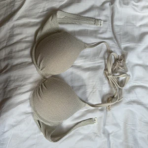 Vit bikiniöverdel från cencored  - Säljer en vit bikiniöverdel från cencored med vadderade kupor och knyt i nacken. Bikinin har en ribbad struktur och är i syntetmaterial. Perfekt för sommaren!