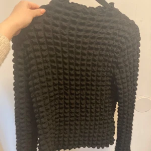 Svart strukturerad tröja från Wera - Säljer en svart långärmad tröja från Wera med unik strukturerad yta som ger ett coolt och trendigt intryck. Perfekt till både jeans och kjol. Tröjan har rund hals och är i ett mjukt material.