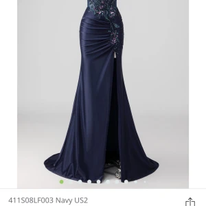 Marinblå balklänning med paljettdetaljer - Säljer en marinblå långklänning med smala axelband och figurnära passform. Klänningen har vacker paljett- och broderidetalj upptill samt drapering över höften. Perfekt för bal eller fest. Axelbanden går att ta av om man vill ha den utan band