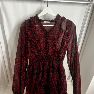 Svart och röd klänning med volang från DeFacto - Säljer en svart klänning med röda leopardmönster från DeFacto. Klänningen har långa ärmar, volangdetaljer vid halsringningen och midjan är markerad med resår. Perfekt för dig som gillar djurmönster och vill sticka ut. Orginal pris 1300 har jag för mig! Pris går att diskutera❤️❤️