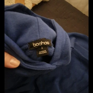 Blå mjukisbyxor från Boohoo - Mysiga blå mjukisbyxor från Boohoo med trycket 'Dept Athleisure Club' på benet. Byxorna har en klassisk passform och är perfekta för en avslappnad stil. Matchar med hoodie i samma färg för en komplett look.