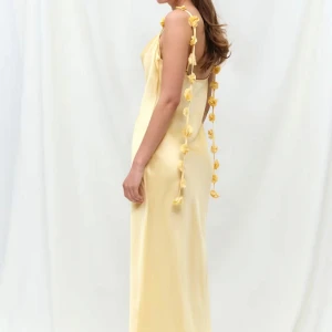 Ljusgul klänning - Säljer denna populära ljusgula långklänning med smala axelband dekorerade med blommor i satin. Perfekt till sommarens festligheter. Storlek 38