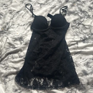 Svart spetsklänning från H&M - Säljer en svart kortklänning från H&M med tunna axelband och vadderade kupor. Klänningen är täckt av spets och har en feminin, figurnära passform. Perfekt för dig som gillar en elegant och stilren look.
