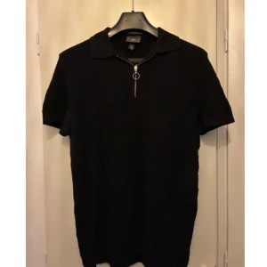 Svart pikétröja med dragkedja - Svart pikétröja från H&M med korta ärmar och dragkedja framtill. Klassisk krage och stilren design som passar till många tillfällen. Perfekt för dig som gillar en enkel men snygg look.