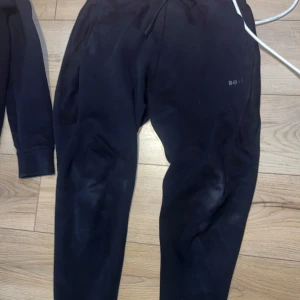 Svart hoodiejacka från BOSS - Svart hoodiejacka från BOSS med dragkedja framtill och huva med dragsko. Jackan har diskret BOSS-logga på bröstet och är tillverkad i mjukt material som känns skönt mot huden. Perfekt för en avslappnad och stilren look.