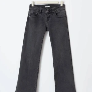 Gråa Y2K wide jeans från Gina Tricot - Säljer ett par gråa Y2K-inspirerade jeans från Gina Tricot i storlek 42. Modellen är wide med låg midja och klassiska femficksdetaljer samt bakfickor med lock och knapp. Helt nya och oanvända, säljs för 70kr