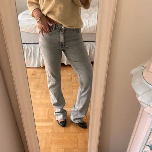Grå raka jeans med medel midja - Snygga ljusgrå jeans med raka ben och klassisk femficksmodell. Jeansen har medel midja och en avslappnad, straight fit som ger en chill vibe. Perfekta att styla med sneakers eller boots för en clean look.