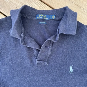  Ralph Lauren pikétröja - Säljer denna feta mörkblå pikétröja från Ralph Lauren. Modell är i Classic fit som är perfekt till jeans eller shorts. Enkel och stilren design som alltid funkar. Perfekt till nu på sommaren! Skick 7/10, inte använts så mycket av mig. Bara att höra av sig vid frågor!
