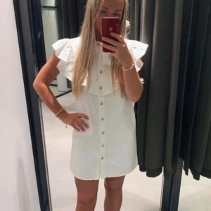Volang jeans klänning - Super söt jeans klänning i vitt med volanger, inga defekter och knappt använd. Storlek M men rätt liten i storleken. 