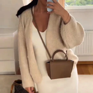 Beige stickad kofta - Mysig och oversized beige stickad kofta med lång ärm och öppen framtill. Perfekt att slänga över en klänning eller topp för en chill och stilren look. Jackan har en enkel design och är supermjuk, vilket gör den till ett måste i garderoben. 