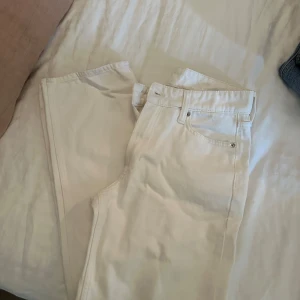 Vita baggy jeans från hm - Säljer ett par vita baggy jeans från hm  med låg midja. Jeansen har klassisk femficksdesign och raka ben. Perfekta för en avslappnad och trendig look. Materialet är denim och färgen är helt vit.