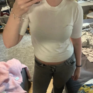 Vit croppad stickad tröja - Säljer en vit, croppad stickad tröja från 157 med korta ärmar och rund hals. Tröjan har en clean och enkel look, perfekt till jeans eller kjol. Mjuk och skön mot huden, passar dig som gillar stilrena basplagg.