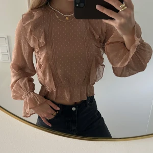 Beige volangblus med mönster - Supersöt beige blus med små prickar, volangdetaljer längs axlar och bröst samt volangkant nertill. Långärmad med lätt transparent tyg och resår vid ärmslut och midja 🫶🏼🥰