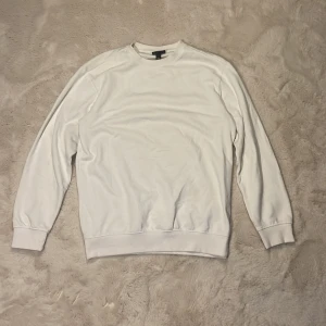 Vit sweatshirt från H&M  - Enkel och stilren vit sweatshirt från H&M i relaxed fit. Tröjan har rund halsringning, långa ärmar och ribbade muddar vid ärmslut och nederkant. Perfekt för en clean och avslappnad look.