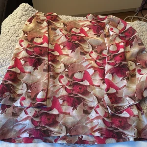 Blommig blus från Rodebjer XS - Snygg blommig blus från Rodebjer i återvunnen polyester. Blusen har ett färgstarkt mönster i rosa, rött och beige toner och är i fin klassisk  modell. 