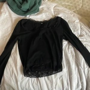 Svart långärmad topp med spetsdetaljer - Svart långärmad topp med snygga spetsdetaljer längs halsringningen och nederkanten. Storlek s, ganska kort vid magen. Kanske använd 1 gång.