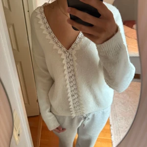 Vit stickad tröja med spetsdetalj - Superfin vit fluffig stickad tröja med v-ringning och spets längs halsringningen och framtill.💞 Säljer då jag behöver pengar!🩵 Nypris: 499🩵