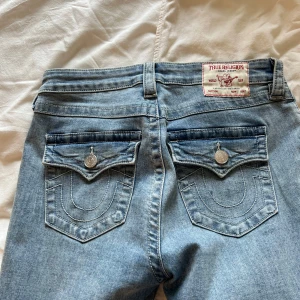 True Religion Becca Bootcut Jeans - Snygga ljusblå jeans från True Religion, modell Becca med bootcut och medelhög midja. Klassiska femficksdetaljer, snygga bakfickor med silverknapp  samt tydliga sömmar. Tillverkade i mjukt denim för en skön känsla.  storlek 28 , man får tänka på att storlekare är anurlunda beroende på vart dom kommer ifrån, byxorna är använda 2 gånger och har inga täcken på användning eller slitage, nypris 1299 , säljer så billigt för jag behöver få mer plats i garderoben 🤗💕