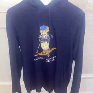 Mörkblå Polo Bear hoodie från Ralph Lauren - Säljer en mörkblå hoodie från Ralph Lauren med Polo Bear-tryck på bröstet där björnen åker skidor. Pris kan diskuteras och byten likaså.