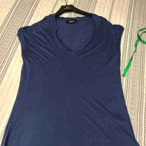 Blå t-shirt från Sisters Point - Snygg blå t-shirt från Sisters Point i storlek XS. Klänningen har v-ringad hals och är tillverkad i mjukt, tunt material som känns skönt mot huden. Modellen är ärmlös och har en enkel, stilren design som är lätt att matcha med accessoarer.