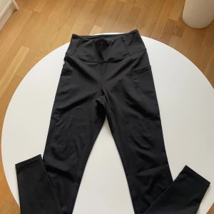 Svarta leggings från H&M Move - Svarta leggings från H&M Move i storlek S. De har hög midja och är gjorda i ett stretchigt syntetmaterial som sitter tight och bekvämt. Perfekta för träning med praktiska fickor på sidorna. Snygg och enkel design som funkar till gymmet eller powerwalken.