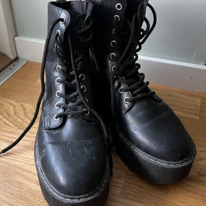 Svarta Boots med Dragkedja - Säljer dessa svarta boots som stängs med dragkedja på sidan och har snöre fram. De är i gott skick med små tecken på användning men inga slitage.