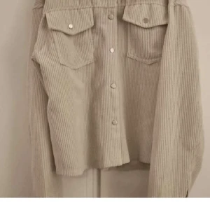 Beige manchester overshirt från SHEIN - Säljer en beige overshirt i manchester från SHEIN, storlek M. Jackan har långa ärmar, två bröstfickor med lock och knappar framtill. Perfekt för lager-på-lager och ger en chill vibe till din outfit.