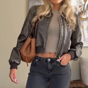 Mörkbrun croppad skinn bomberjacka - Trendig croppad bomberjacka i mörkbrunt skinn med ribbade muddar och dragkedja framtill. Jättesnygg och oanvänd. Passar både M och S beroende på önskad passform (lånade bilder)