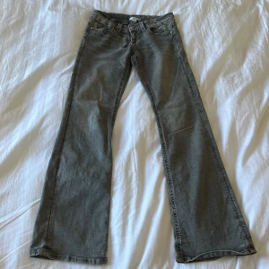 Grå bootcut jeans från Gina Tricot - Snygga grå jeans från Gina Tricot i bootcut-modell. Jeansen har klassisk femficksdesign, lågmidjade  och coola detaljer med flätad söm på bakfickorna. Perfekta till sneakers eller boots för en avslappnad look. Saknar en knapp på fickorna.