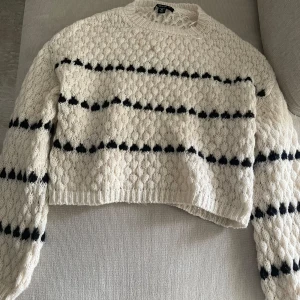 Vit stickad tröja med svarta ränder Amisu - Säljer en vit stickad tröja från Amisu en i storlek XS. Tröjan har svarta horisontella ränder och ett snyggt strukturmönster. Den är långärmad och har ribbade muddar vid hals, ärmslut och nederkant. Perfekt för kyliga dagar!
