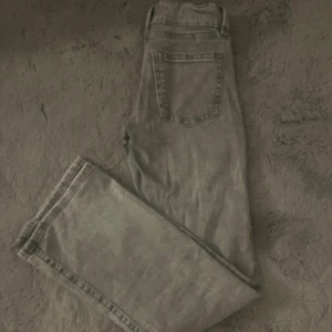 Grå jeans med lätt utsvängda ben från Gina tricot  - Säljer ett par grå jeans med klassisk femficksdesign och lätt utsvängda ben. Jeansen har en enkel look med diskreta sömmar och normal passform. Perfekta för dig som gillar en stilren och avslappnad vibe.