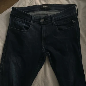 Replay mörkblå jeans Ambass  - Snygga mörkblå jeans från Replay med klassisk femficksdesign och raka ben. Jeansen har en slim passform och är tillverkade i mjukt jeansmaterial med en diskret tvättad look. Perfekta för dig som gillar stilrena och tidlösa jeans. Storlek W32 L33